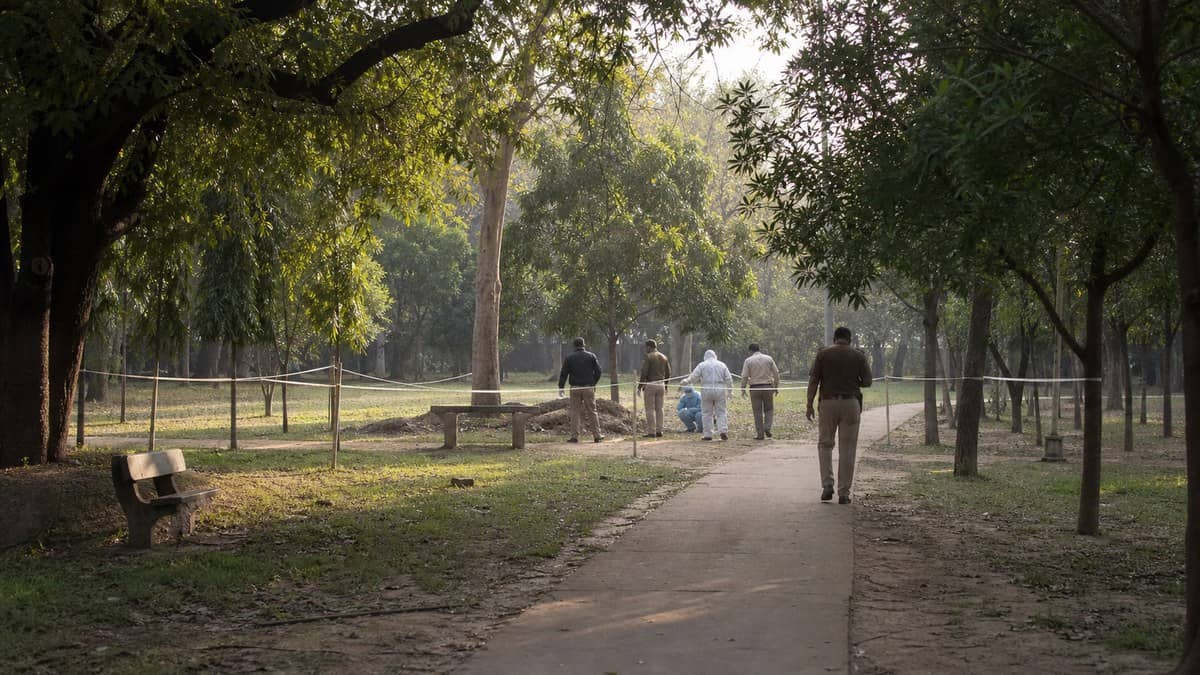 Police investigating a cordoned public area near trees in the Varanasi region