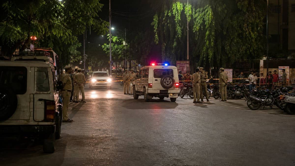 Police vehicles and officers at a cordoned road during a night crime operation in Varanasi