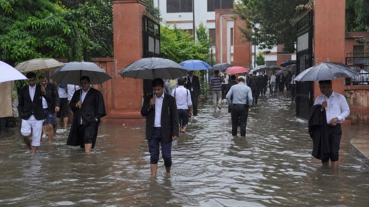 People walking through a waterlogged entrance road near a government office in Varanasi after rain