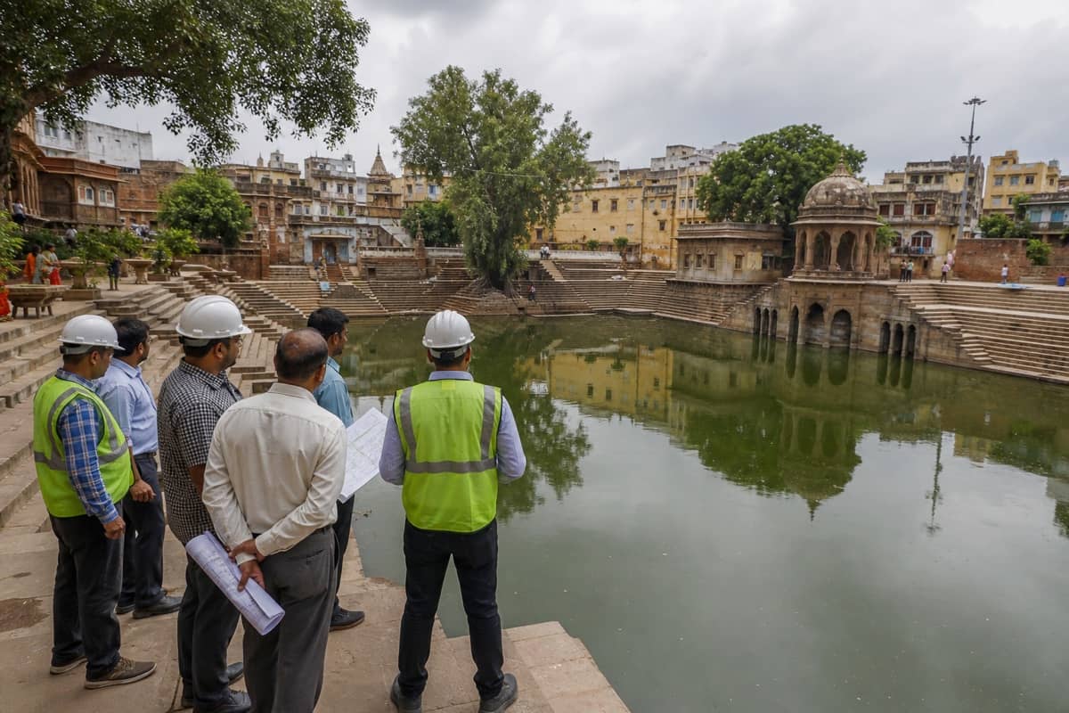 Workers surveying a historic pond and stone steps in Varanasi before ecological restoration