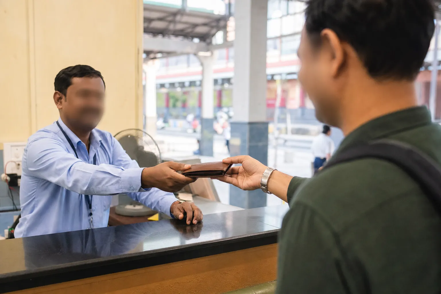 Representative railway-station staff member returning a plain wallet to a traveller