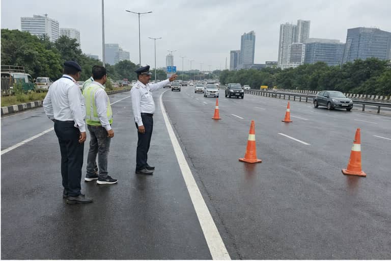 Traffic officers inspecting a wet multilane stretch of NH-48 in Gurugram