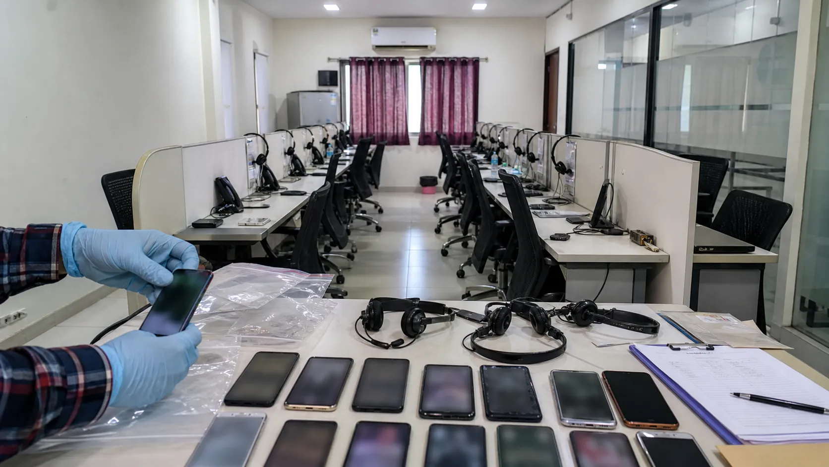 Generic unoccupied call centre desks under police investigation with no visible faces or data