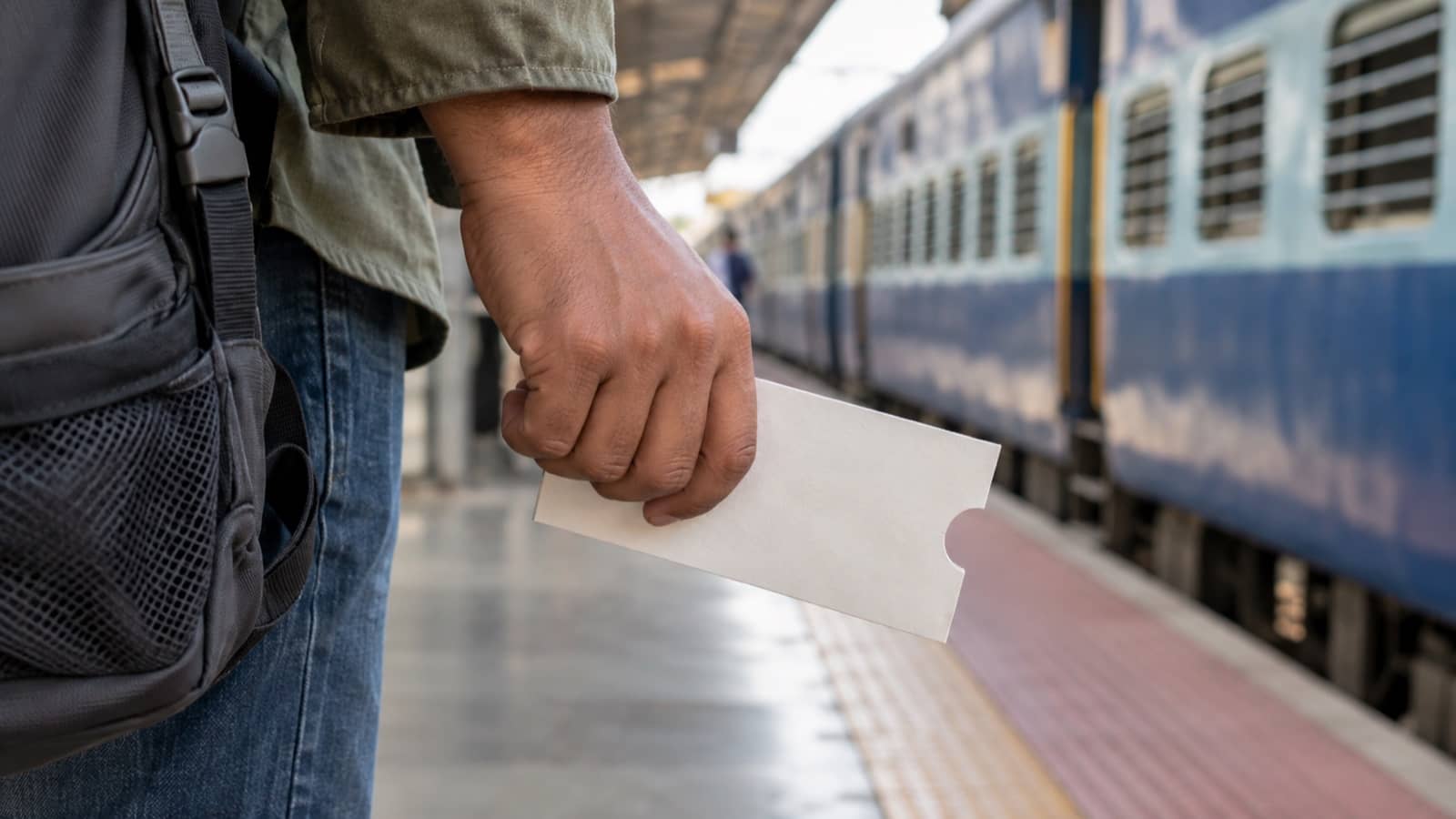 Representative image of a traveller holding an unmarked ticket sleeve on a railway platform