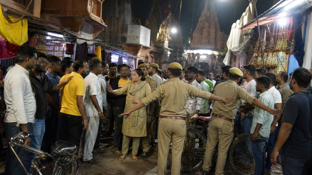 Police separating groups in a crowded old Varanasi market lane at night