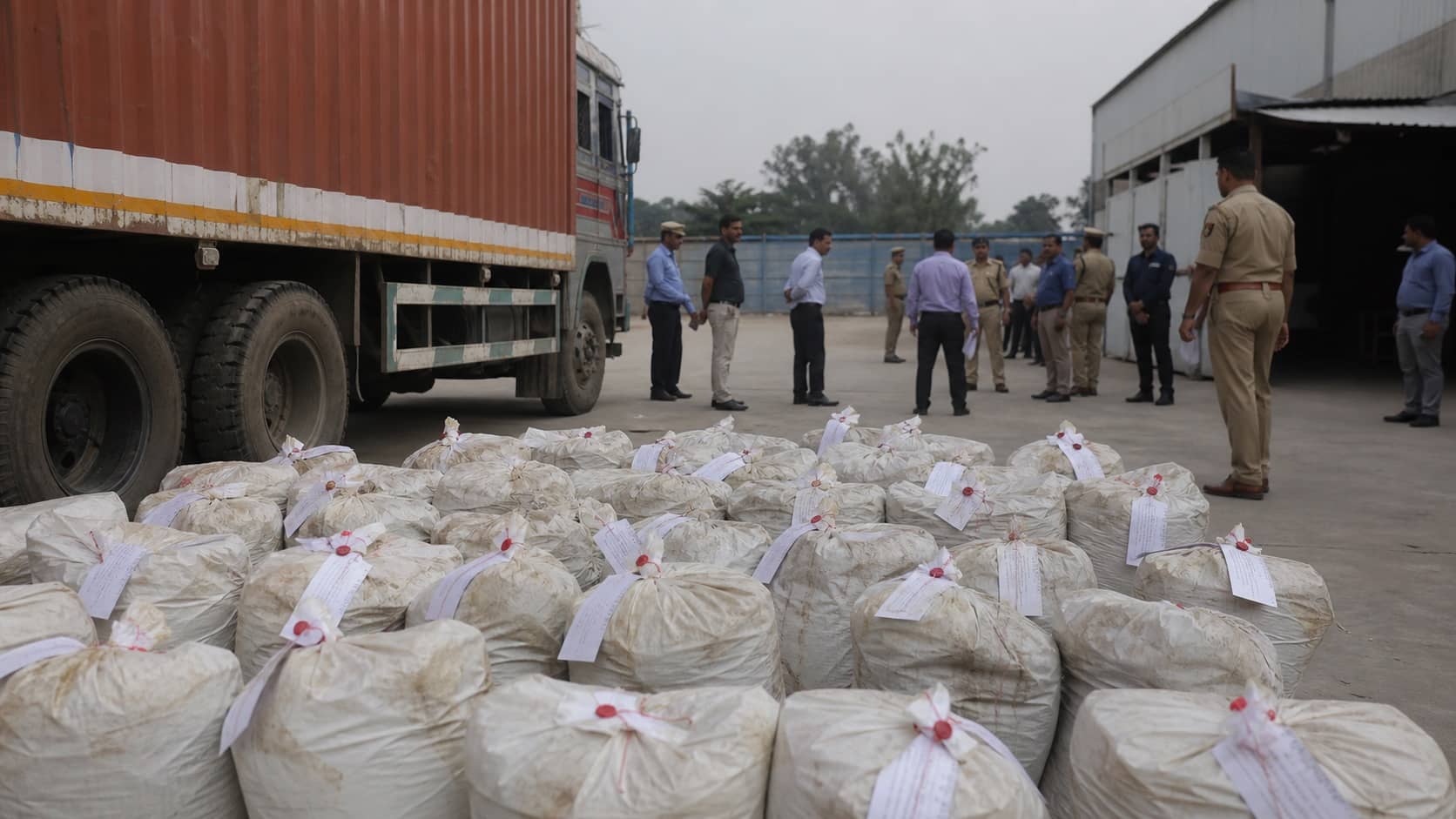 Sealed evidence sacks beside a cargo truck in a secure enforcement yard