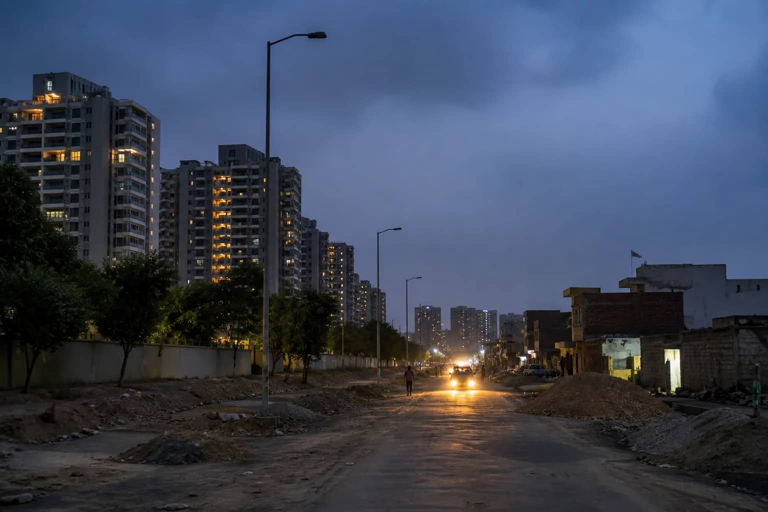 Unlit road beside housing societies in Gurugram Sector 99A at dusk