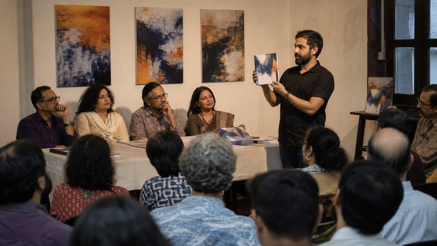 Writers presenting a literary journal to an audience at a small hall