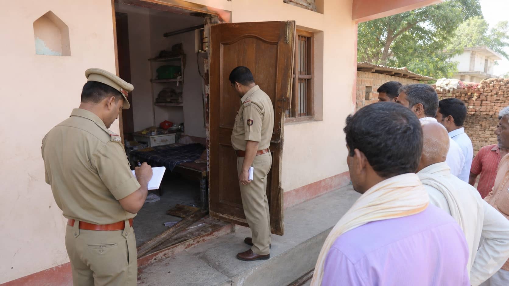 Police examining a damaged doorway after a reported night burglary