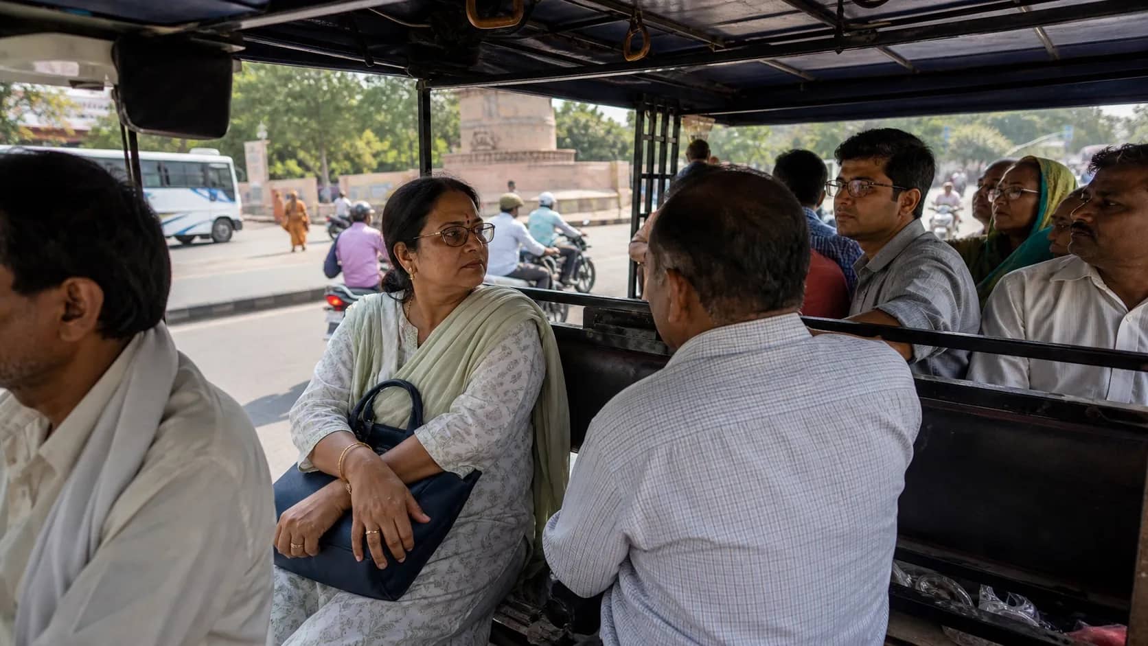 Passengers boarding a crowded e-rickshaw on a Varanasi road