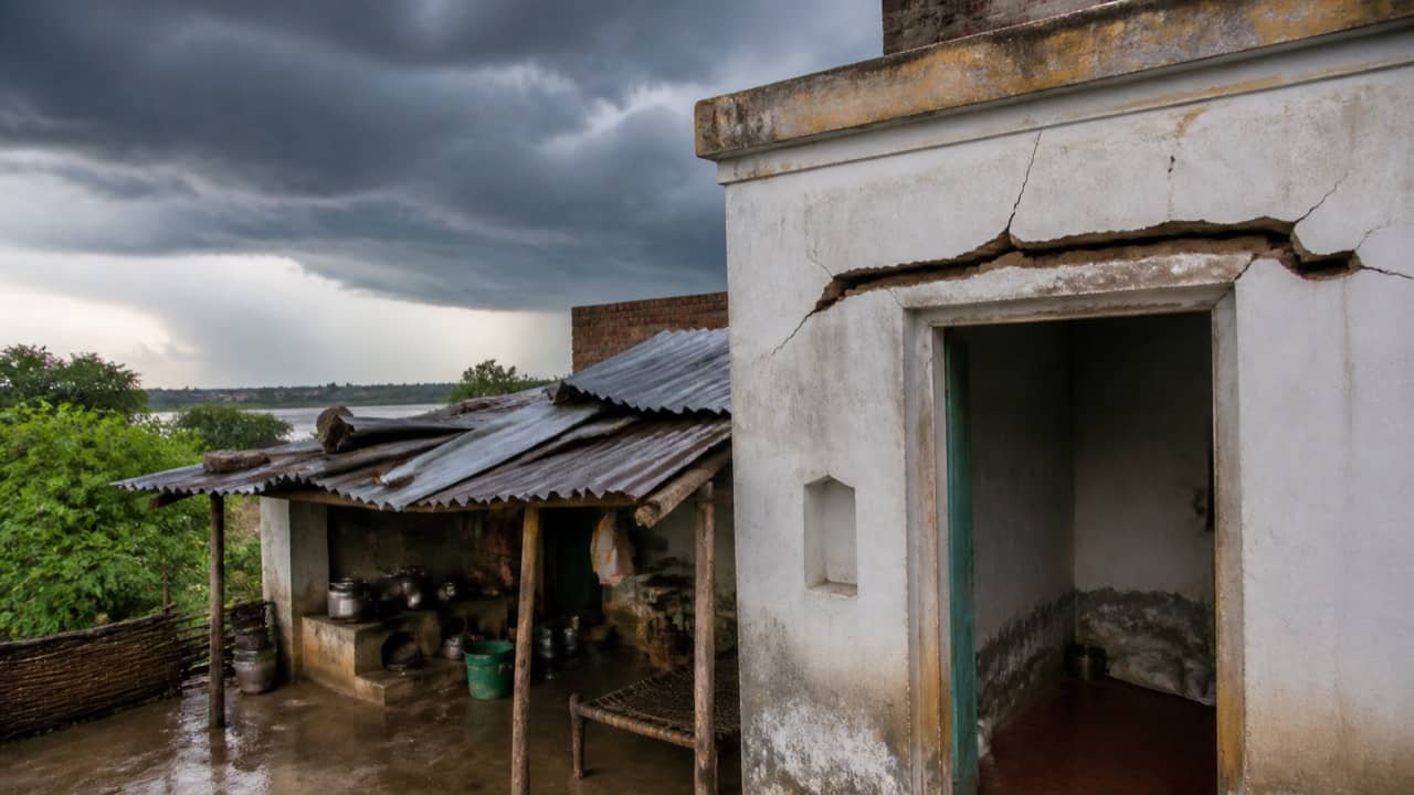 A damaged rural house under dark storm clouds after lightning