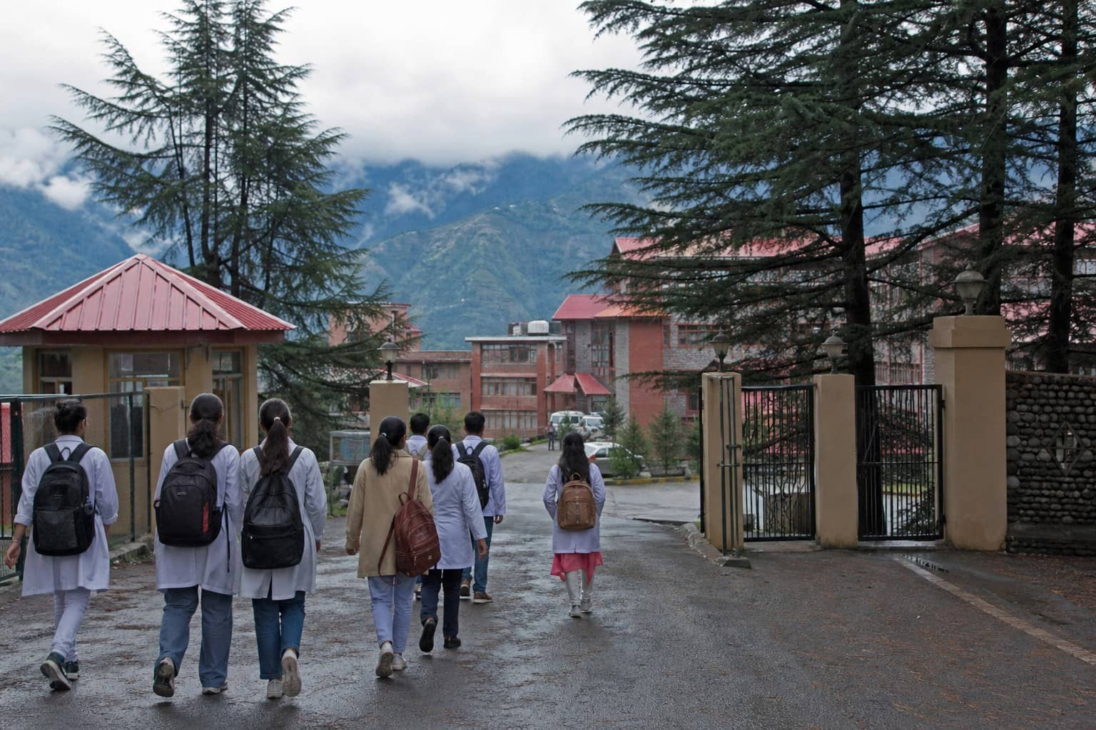 Representational illustration of a Himachal hill medical campus with students walking toward a college gate