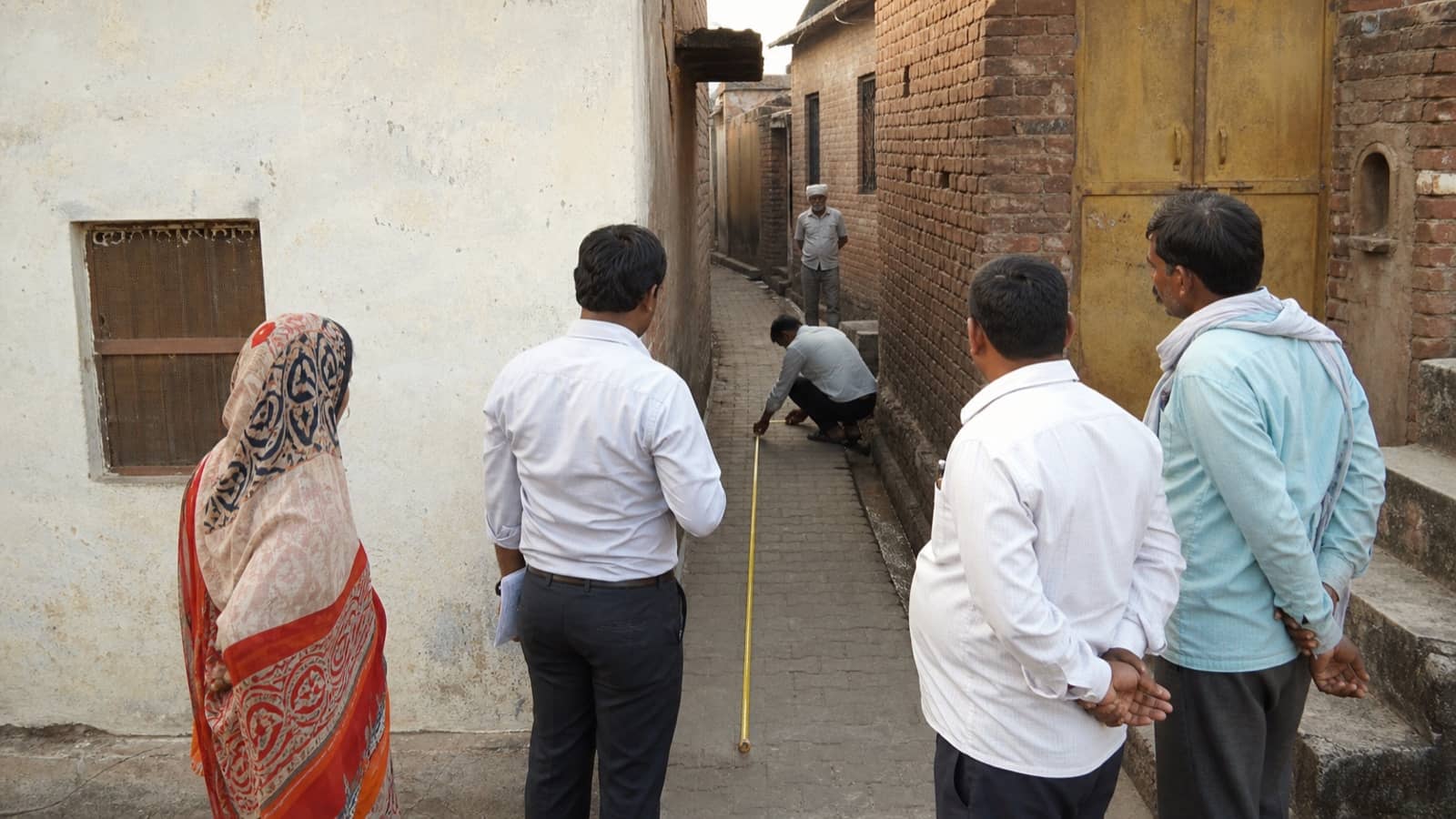 Officials measuring a narrow access lane between homes in rural Varanasi