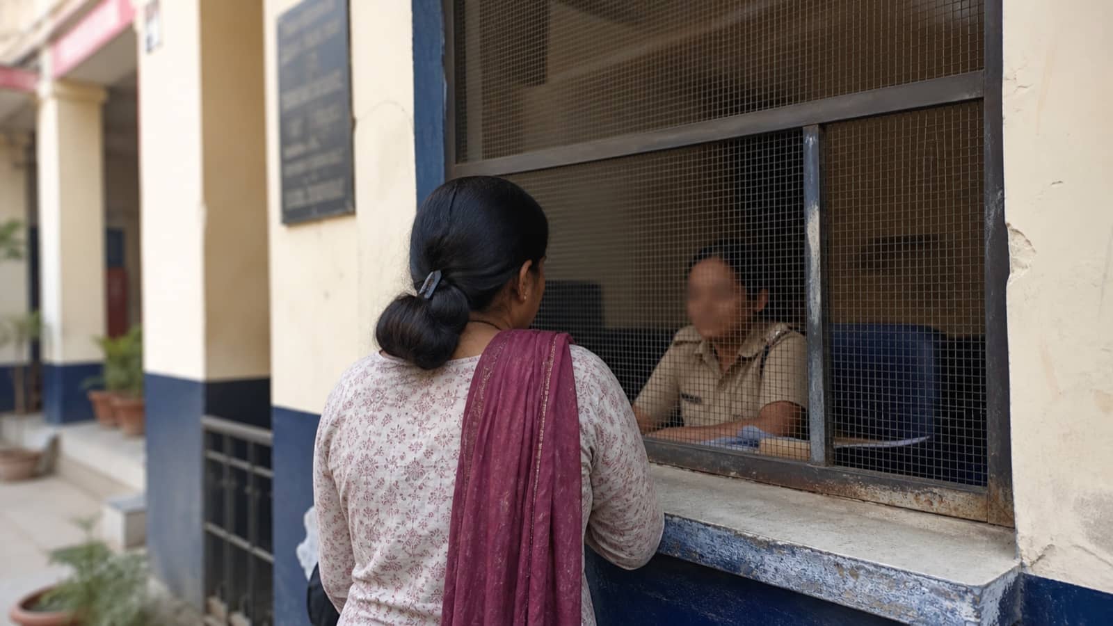 A woman speaking privately with an officer at a police help desk in Varanasi