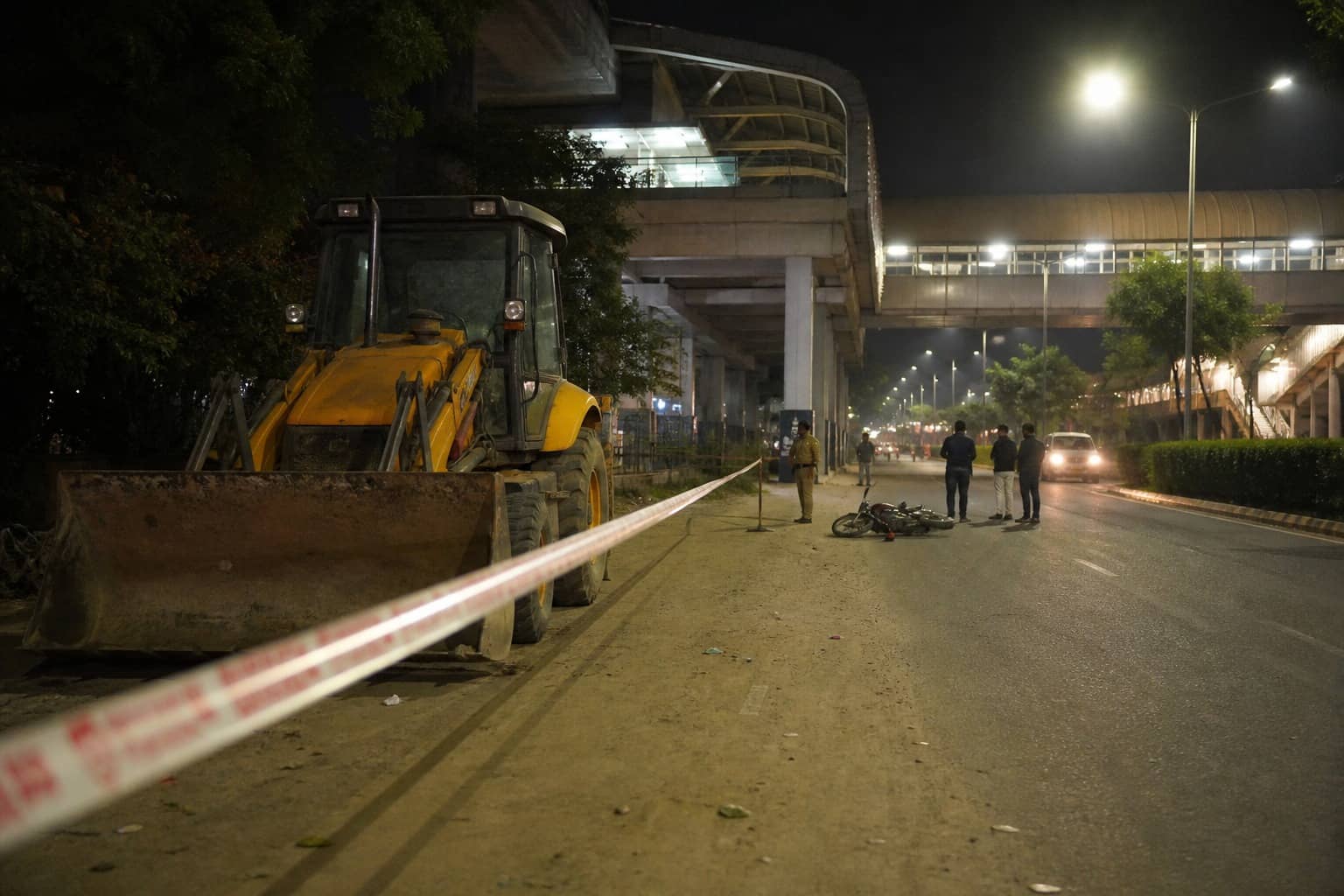 Earthmover and motorcycle on an urban road at night