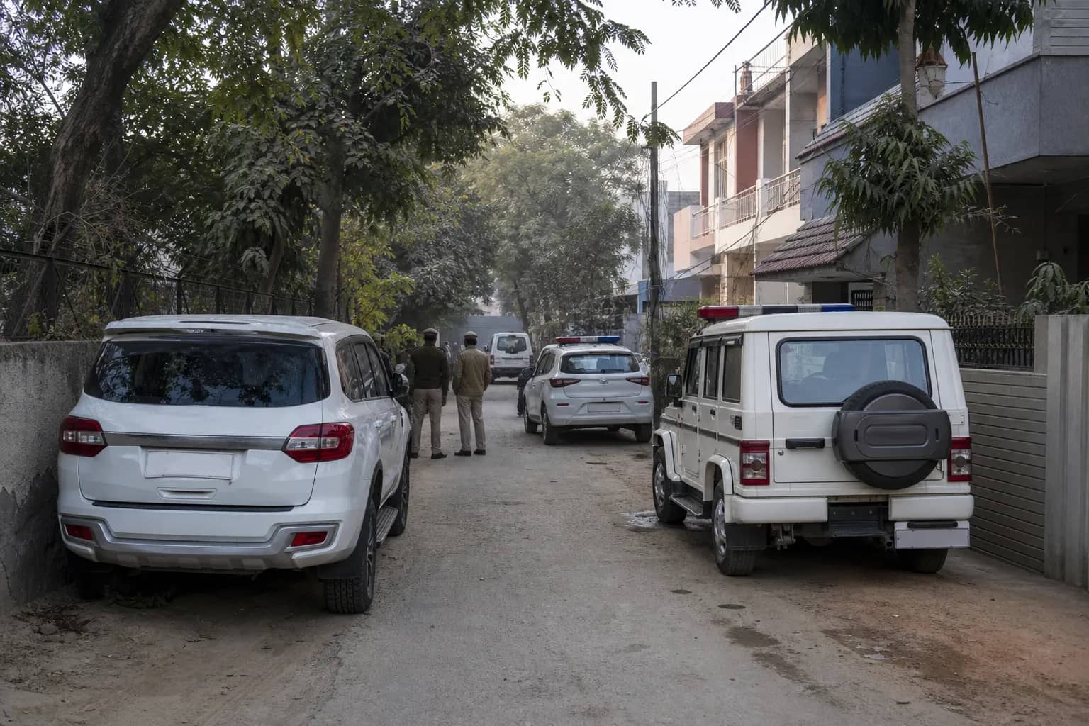 Police vehicles outside a residential lane in Gurugram during an investigation