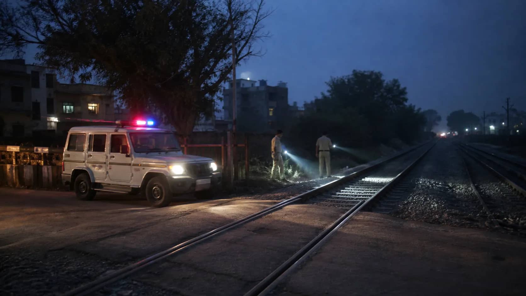 Police torchlight beside an empty railway track near Ashapur at night