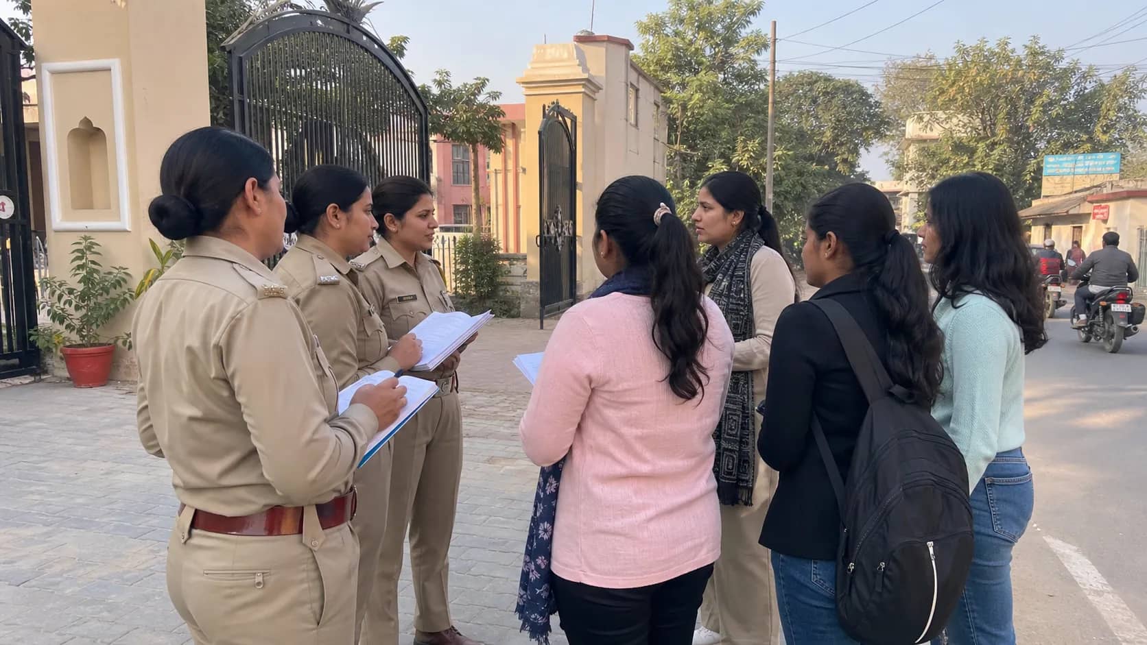 Women police officers speaking with students outside a college gate in Ramnagar