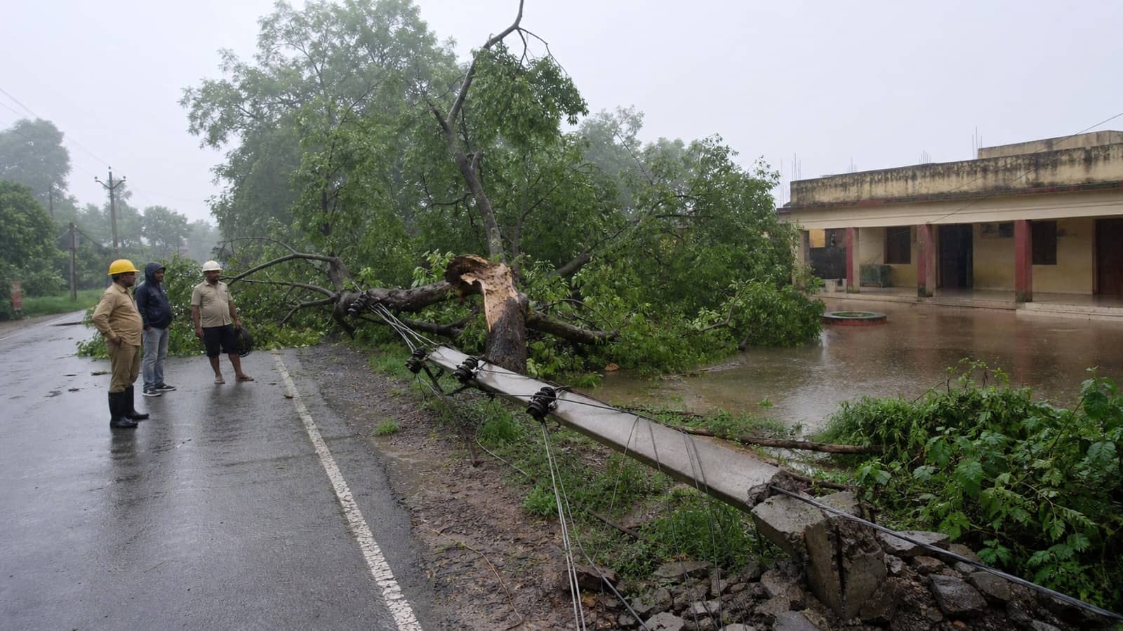 Rainwater around a rural health centre as workers clear a fallen tree