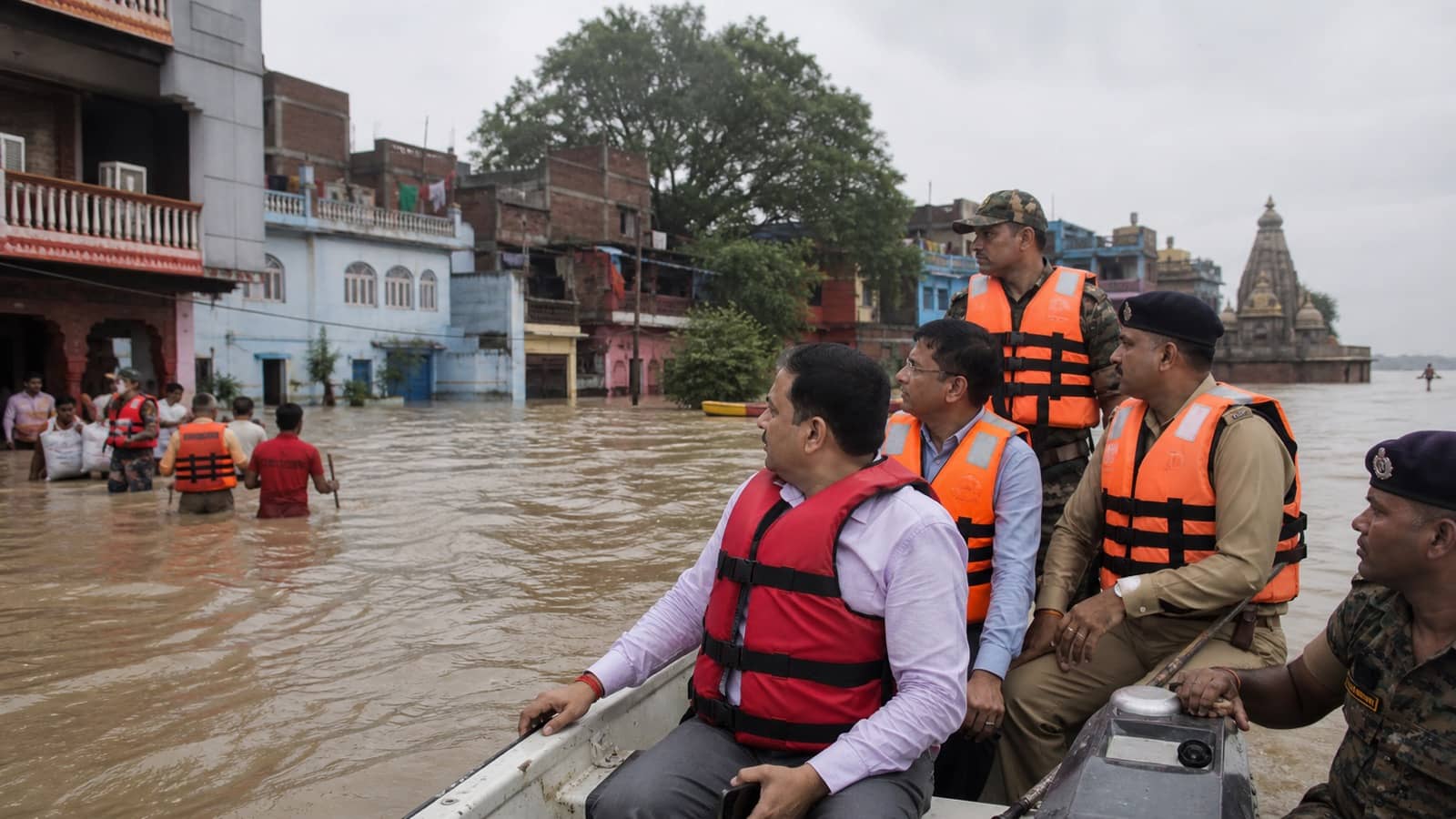 Officials in life jackets inspecting a flooded Varanasi neighbourhood by motorboat