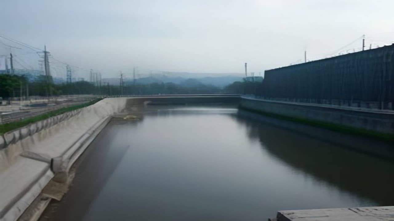 Empty inland river port with concrete platform works and a quiet brown river under overcast sky, no people, no logos, no readable text