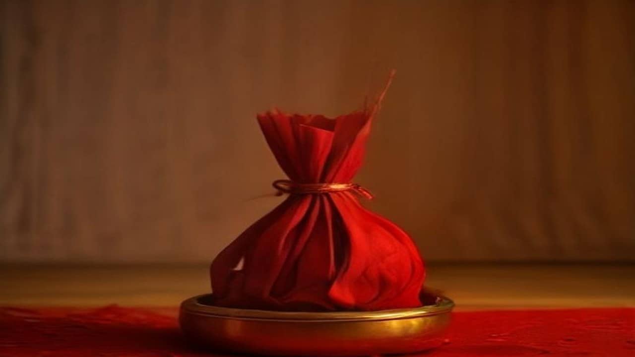 Empty brass kalash with coconut and bel leaves on a red cloth over a wooden puja chowki, no people, no readable text