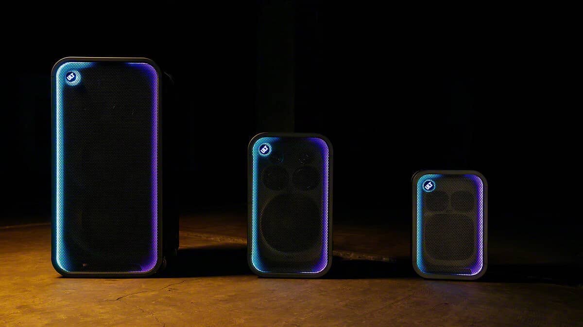 Three black Sony ULT TOWER party speakers of different sizes standing in a row on a dark stage, each with a glowing light ring