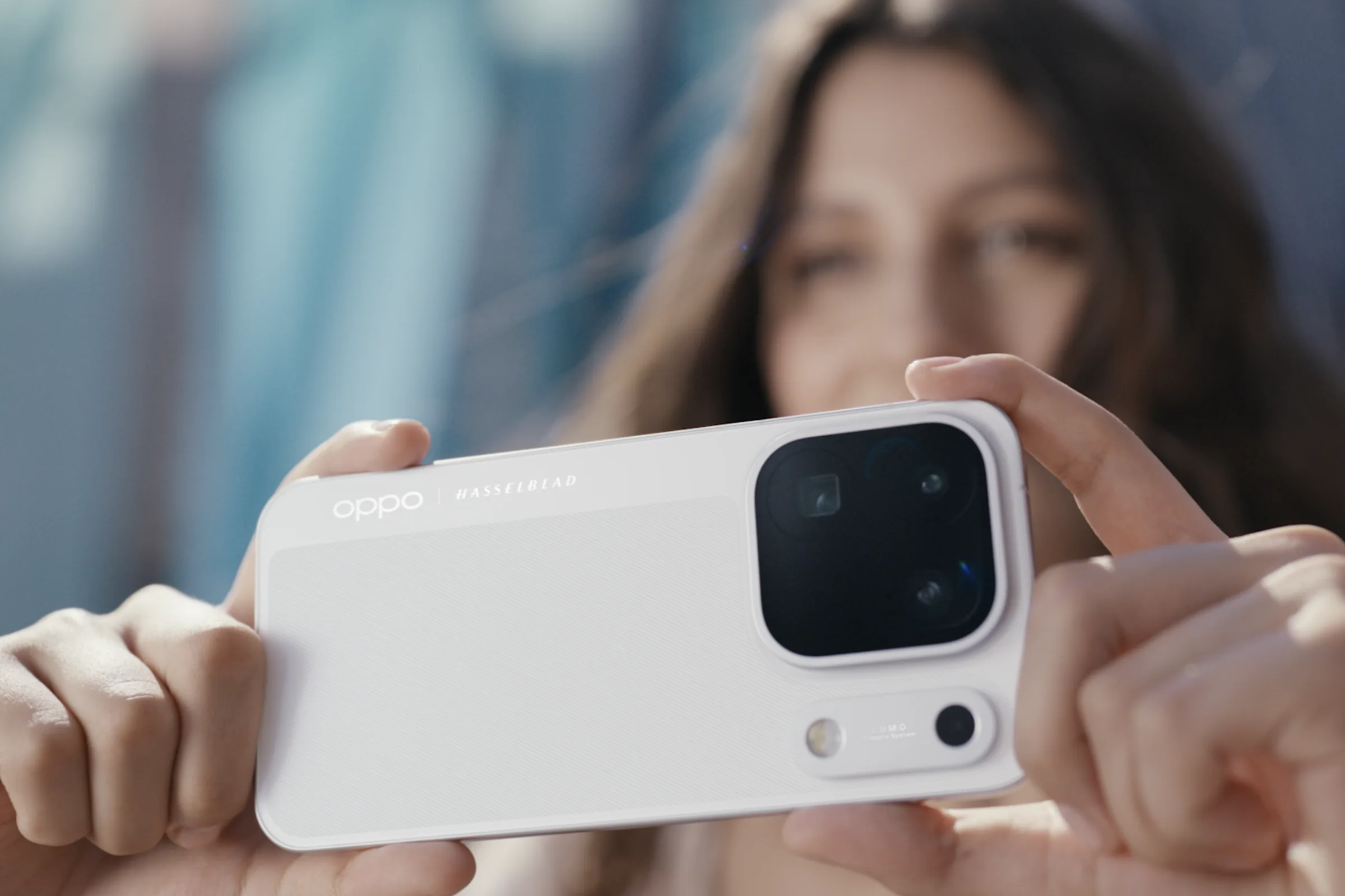 A person holds a white OPPO Find X10 Pro Max horizontally, with its rear cameras facing the viewer.