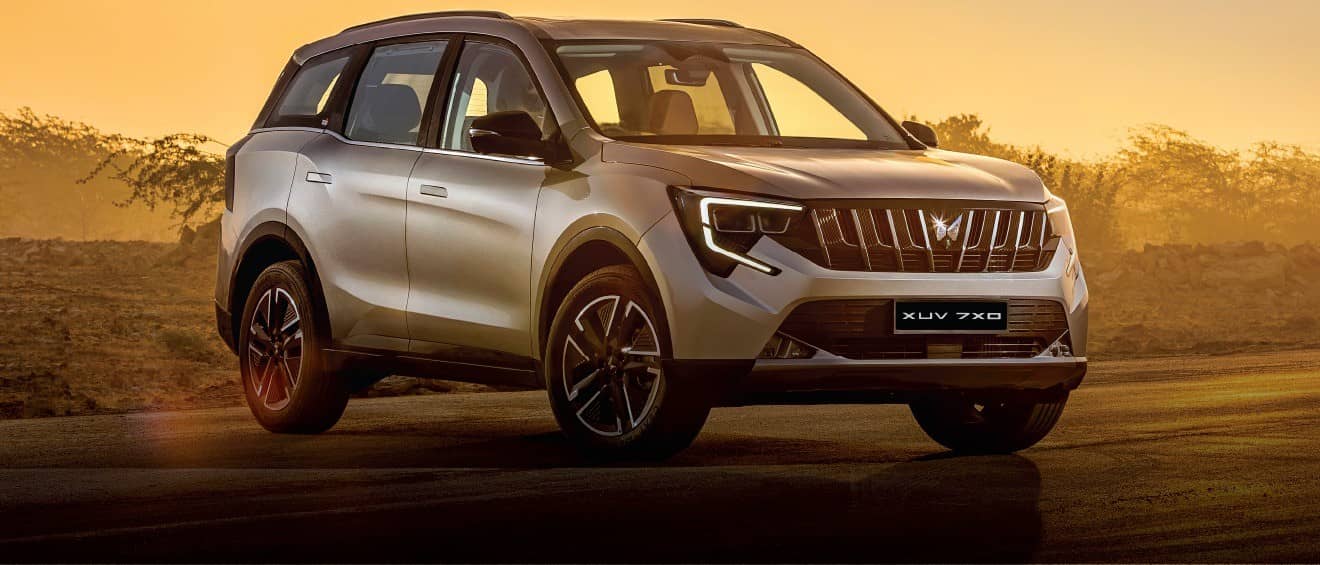 Silver Mahindra XUV 7XO SUV on a road at sunset