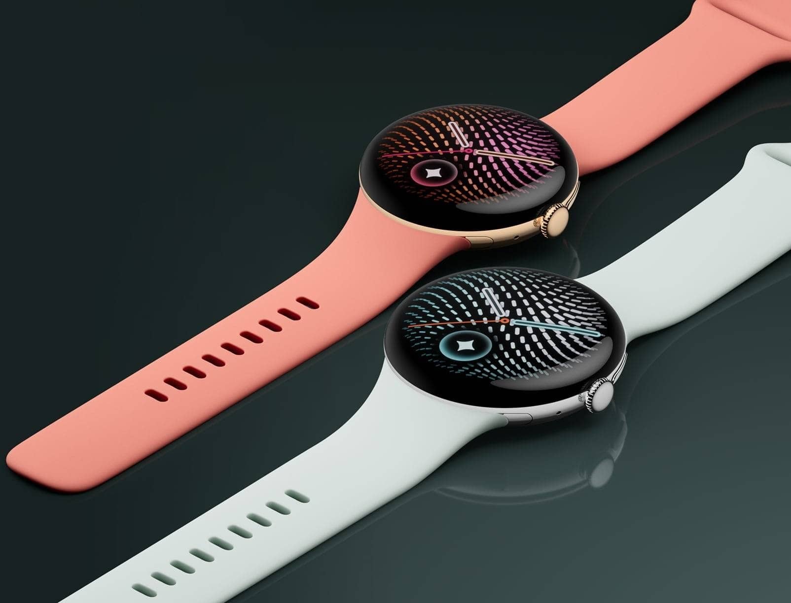 Two Google Pixel Watch 5 smartwatches with coral and white bands lying on a dark surface