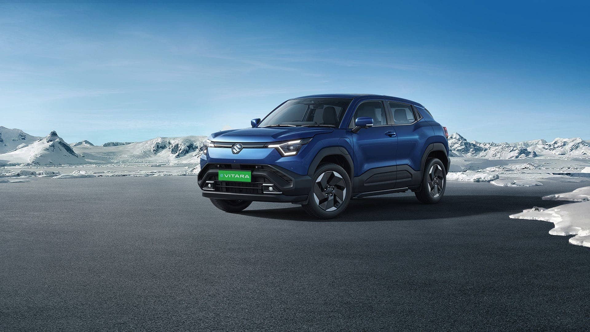 Blue Maruti Suzuki e Vitara electric SUV parked on a road with snowy hills behind