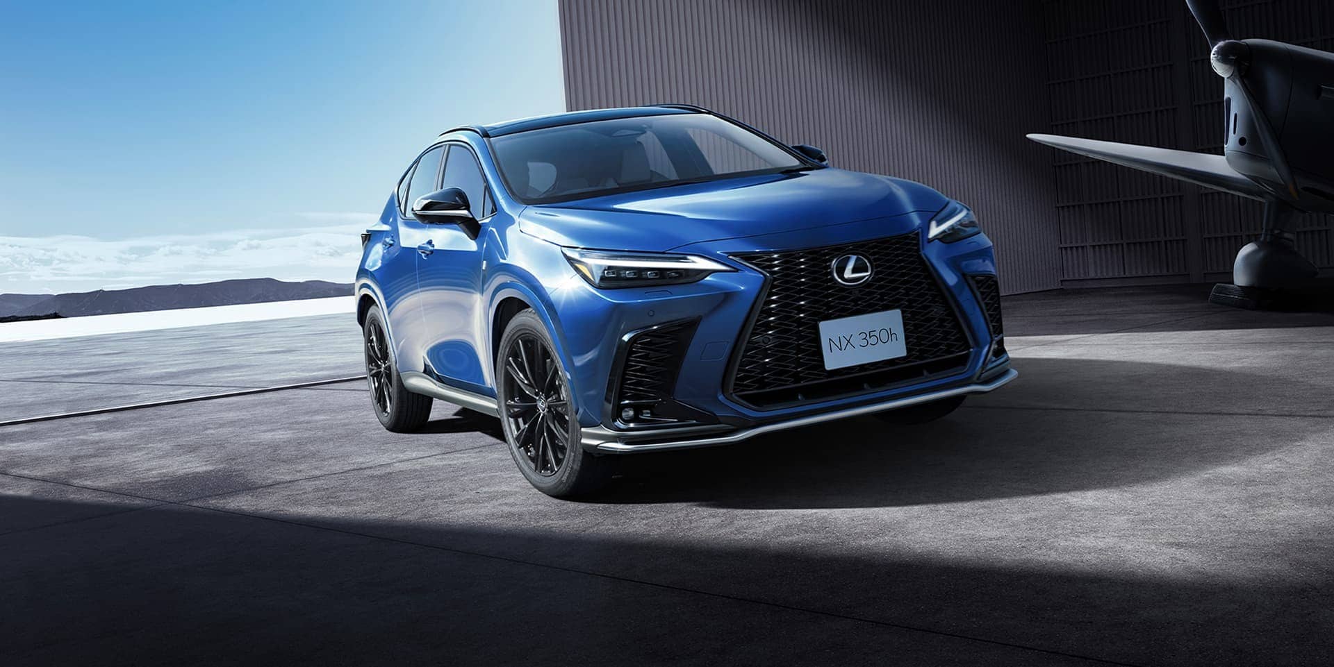 A blue Lexus NX SUV parked on an airfield, front three-quarter view