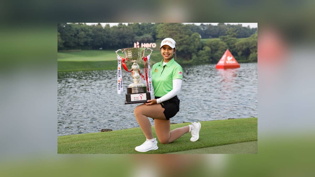 Pornanong Phatlum holds the Women's Indian Open trophy beside a lake at the Gurugram golf course.