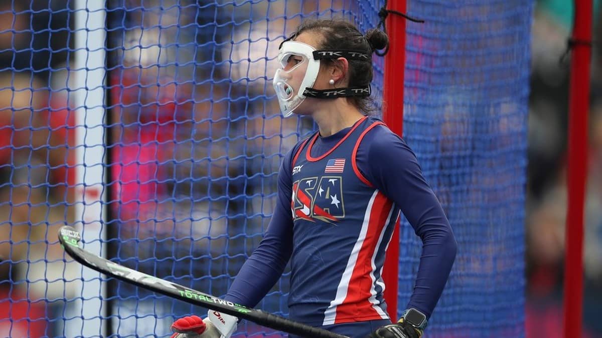 A hockey defender wearing a face mask stands beside the goal before a penalty corner.