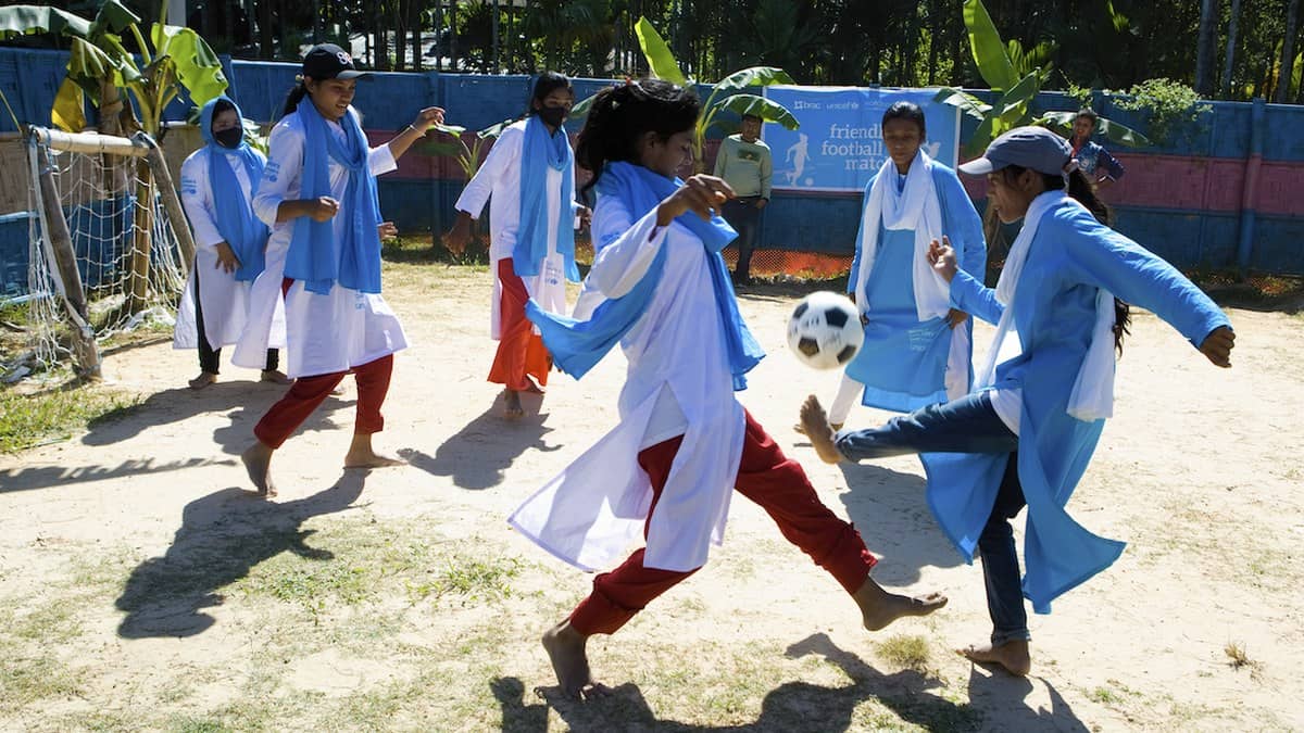 Schoolgirls play football outdoors in a WHO photograph illustrating physical activity.