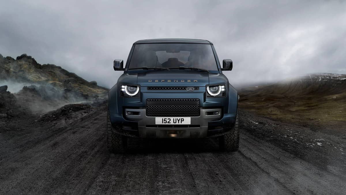 Landscape official photograph of a Defender OCTA driving across muddy ground